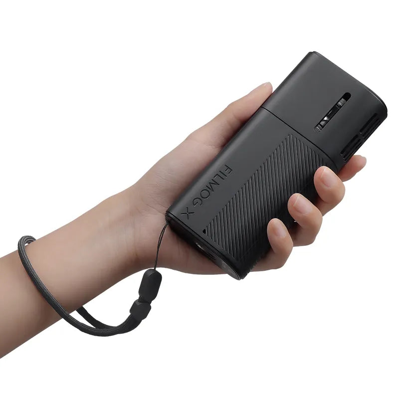 Eine Hand, die eine kompakte tragbare Nebelmaschine FILMOG X mit Handgelenkband hält.