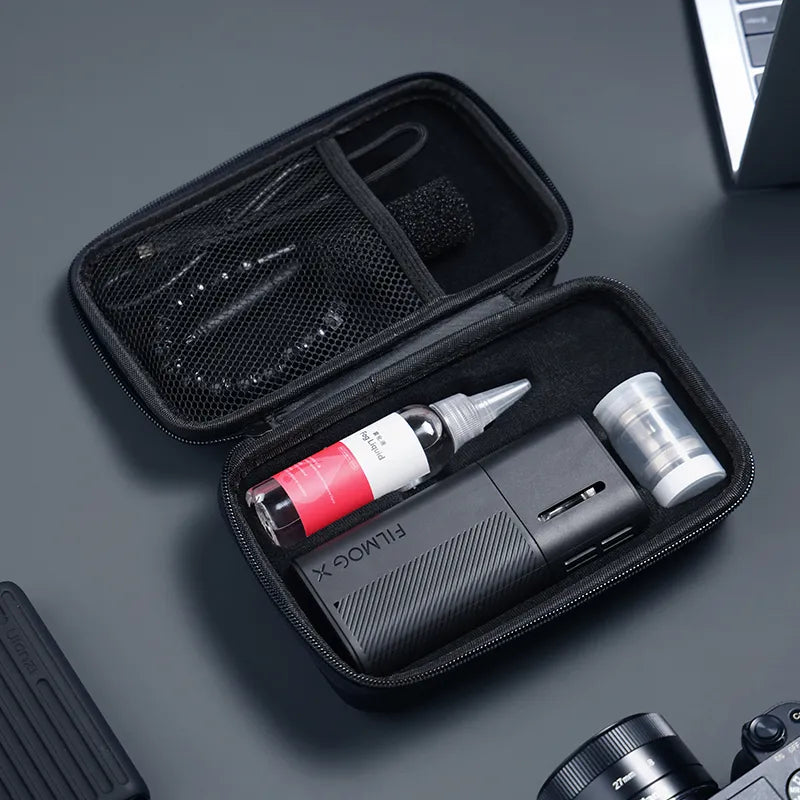 Ein offener Transportkoffer, in dem eine tragbare Nebelmaschine FILMOG X, eine Flüssigkeitsflasche und Zubehörteile übersichtlich angeordnet sind.